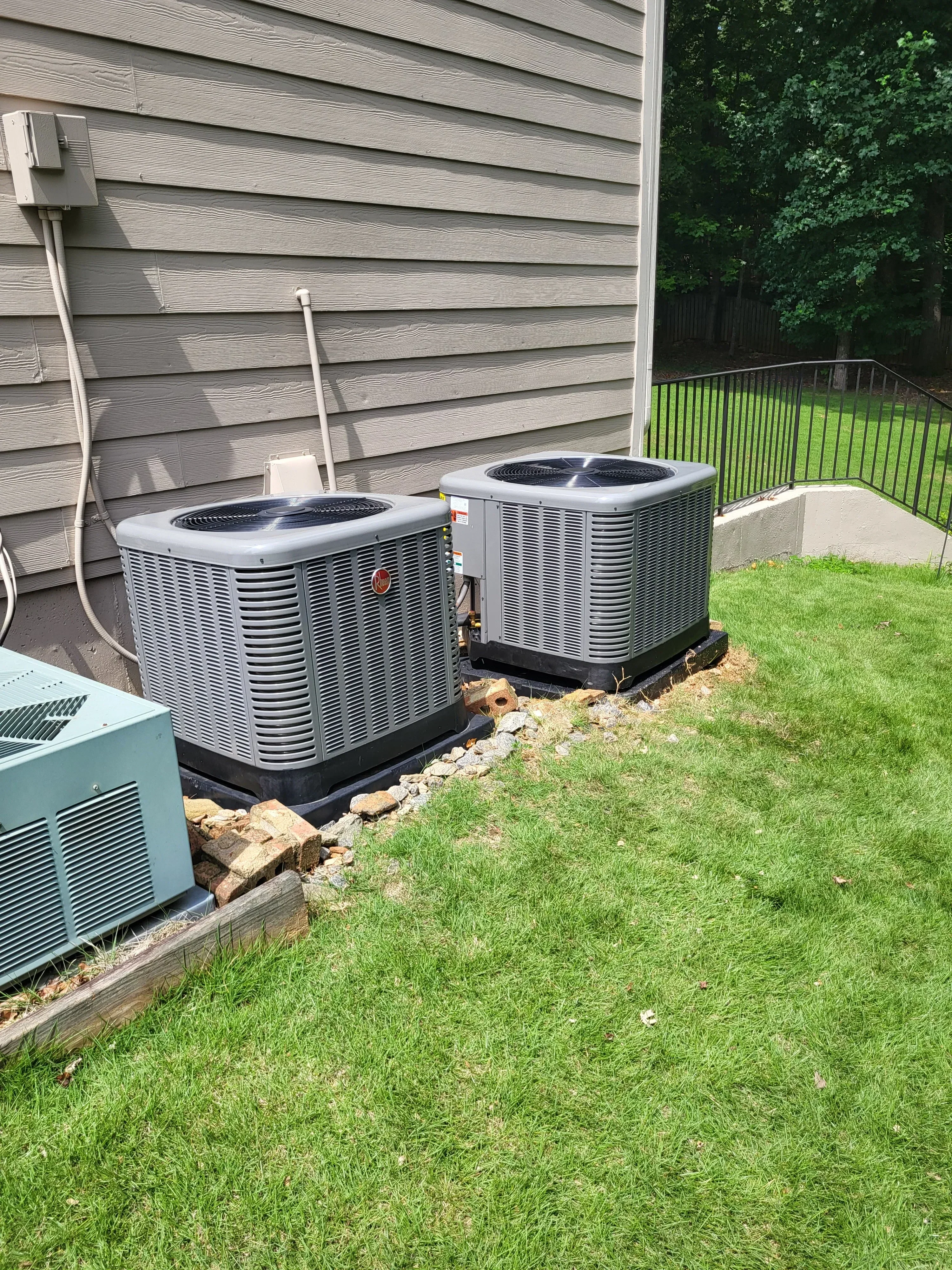 Two heat pump condenser units installed on metal standing seam roof with proper spacing and drainage