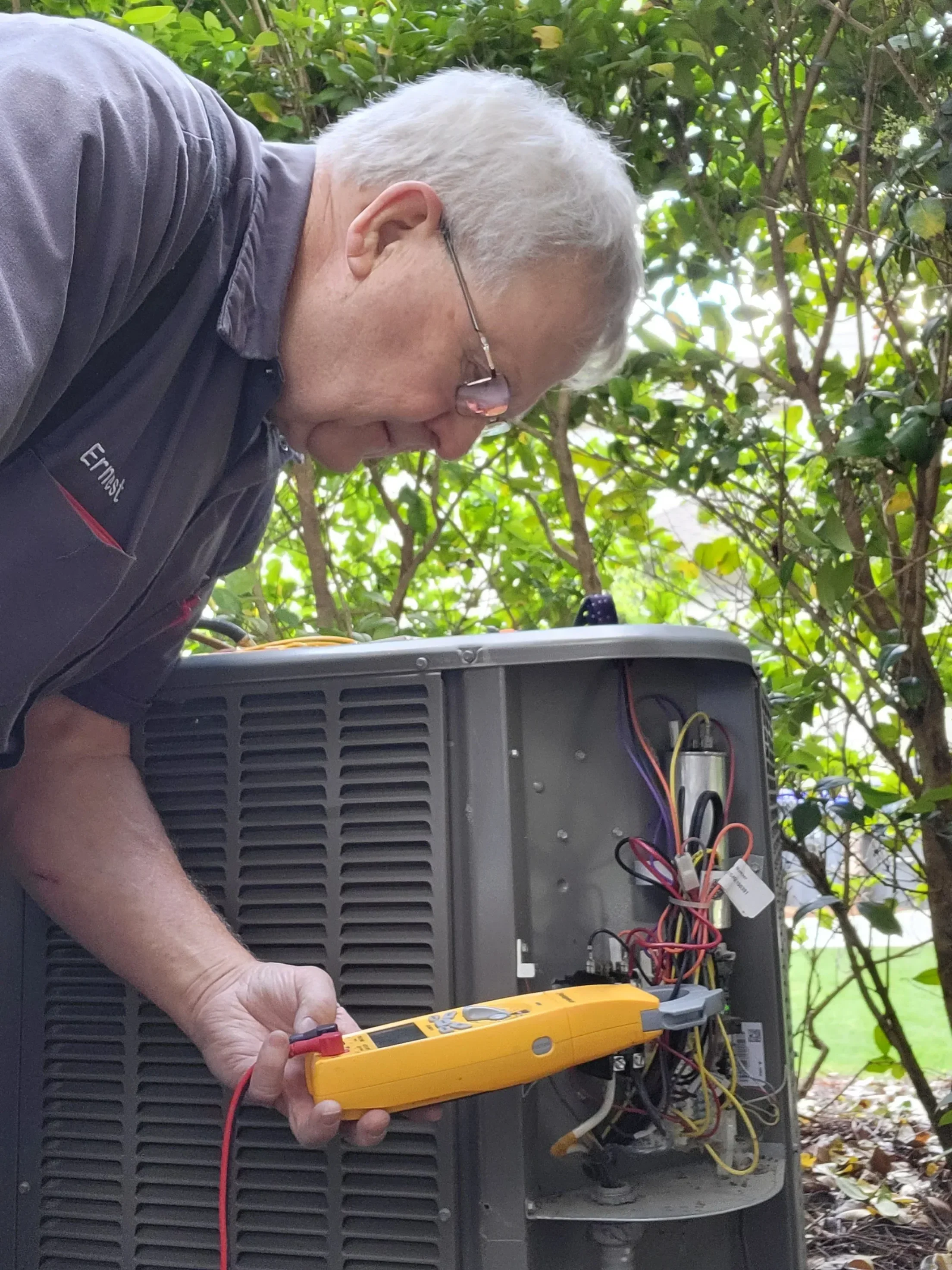Technician using multimeter to test HVAC unit electrical components and wiring