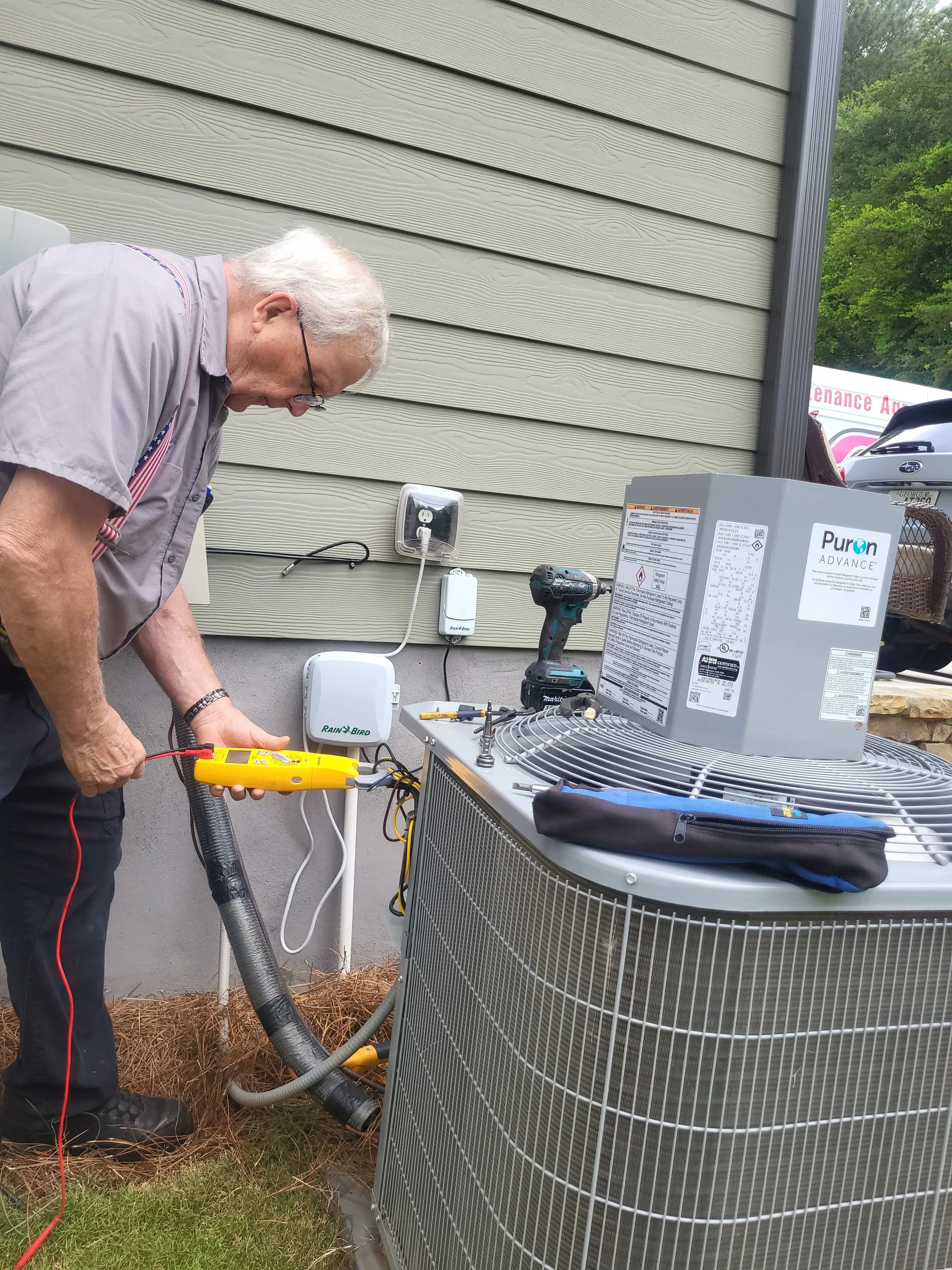 HVAC technician using yellow diagnostic meter to test air conditioning condenser unit connections