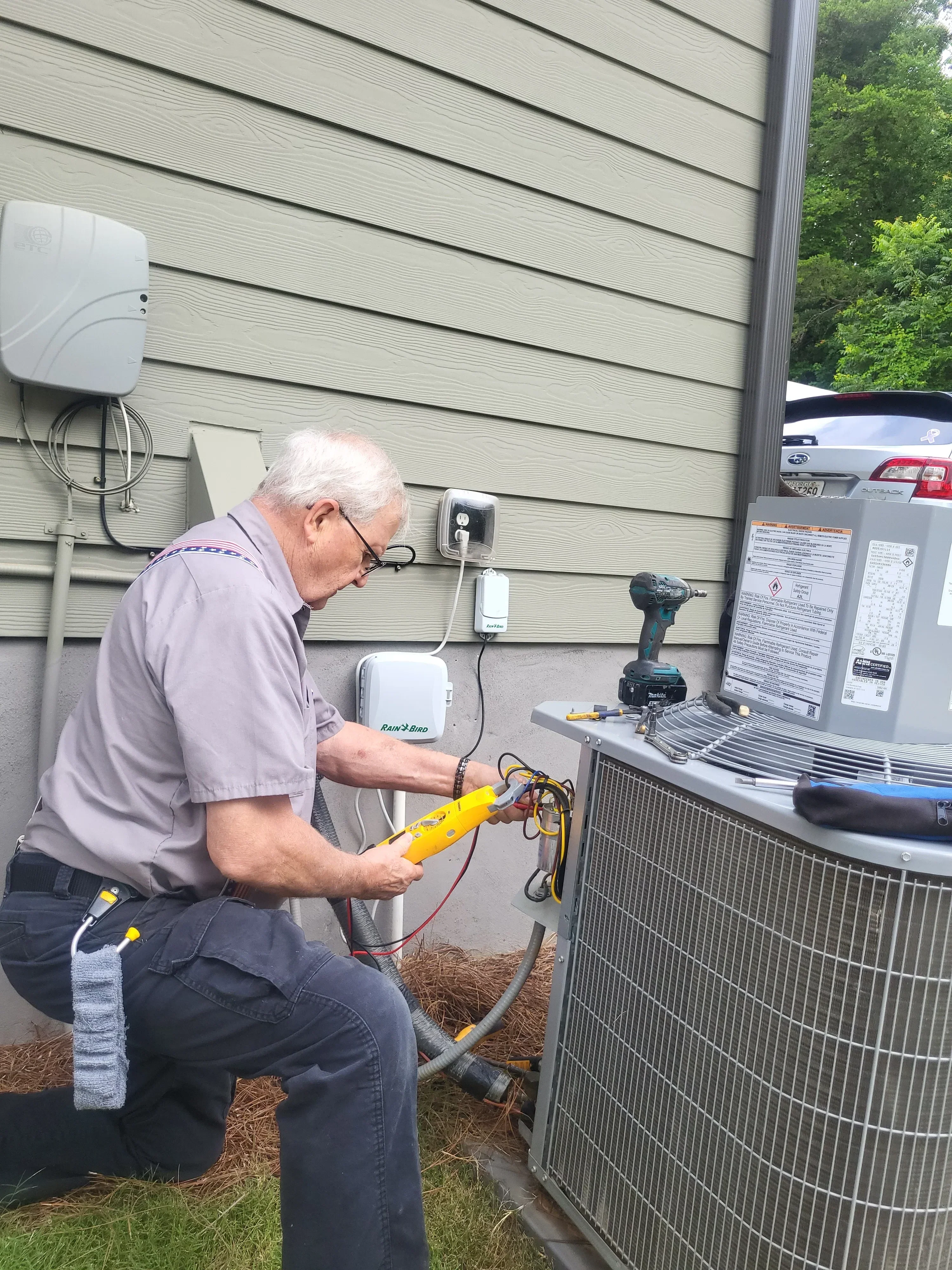 HVAC technician testing AC unit electrical connections with multimeter on metal roof installation